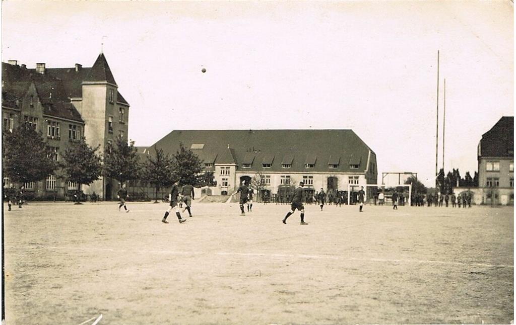 Historische Aufnahme (um 1920): Auf dem Exerzierplatz des Pionier-Regiments 7 in der Kaserne Boltensternstraße in Köln-Riehl spielen englische Soldaten Fußball. Im Hintergrund sind Masten der Funkstation zu sehen.