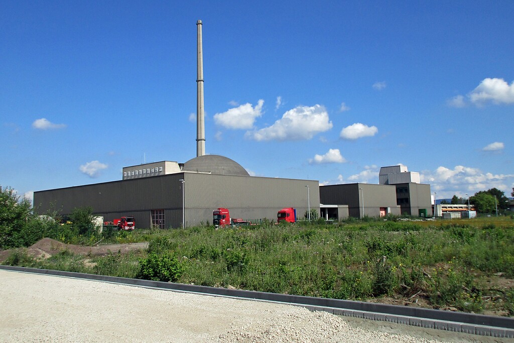 Blick von Süden her auf das Reaktorgebäude und den Abluftkamin des stillgelegten Kernkraftwerks Mülheim-Kärlich, davor befinden sich Betriebsgebäude einer Autokran-Firma (2020).