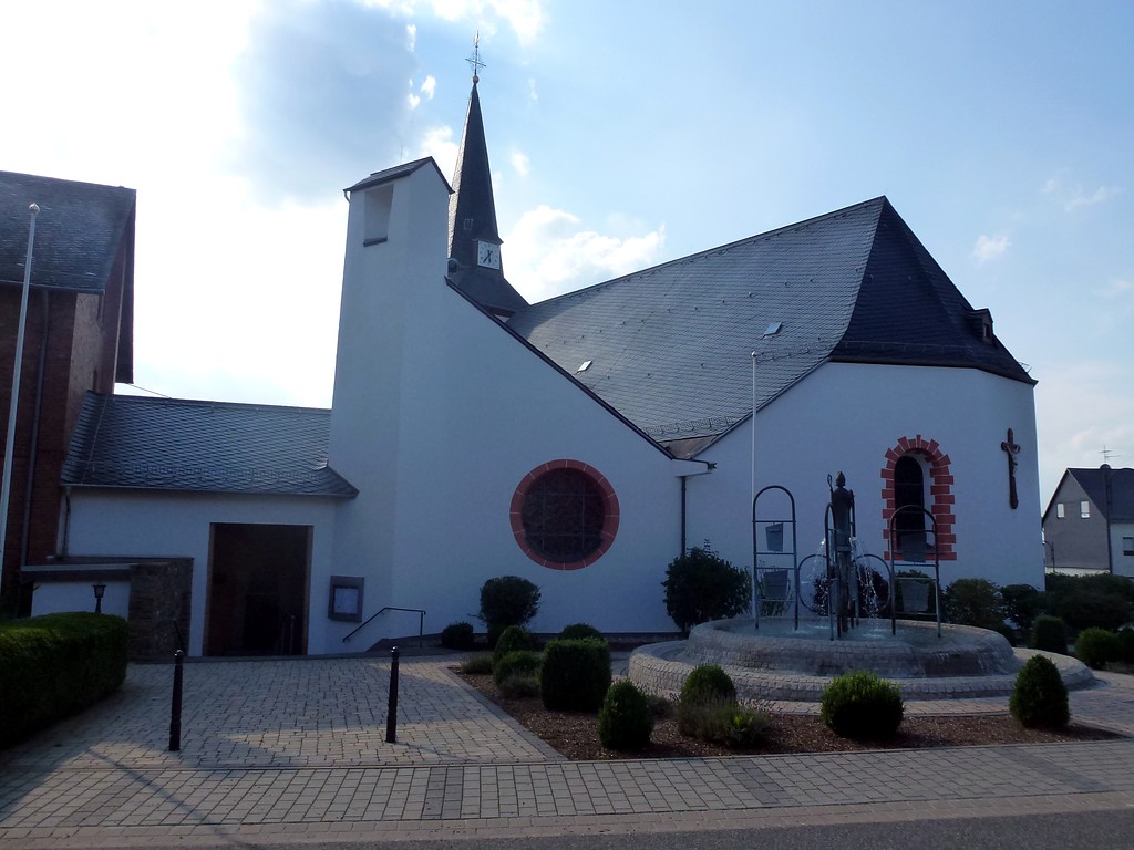 Katholische Pfarrkirche Sankt Lambertus in Halsenbach mit dem Lambertusbrunnen auf dem Kirchenvorplatz (2014)