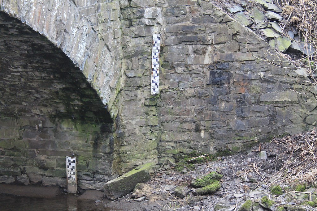 Eine Brücke aus Bruchstein in der Nähe der ehemaligen Sägemühle Mühlenau (2012). Zu erkennen ist der Pegelmesser.