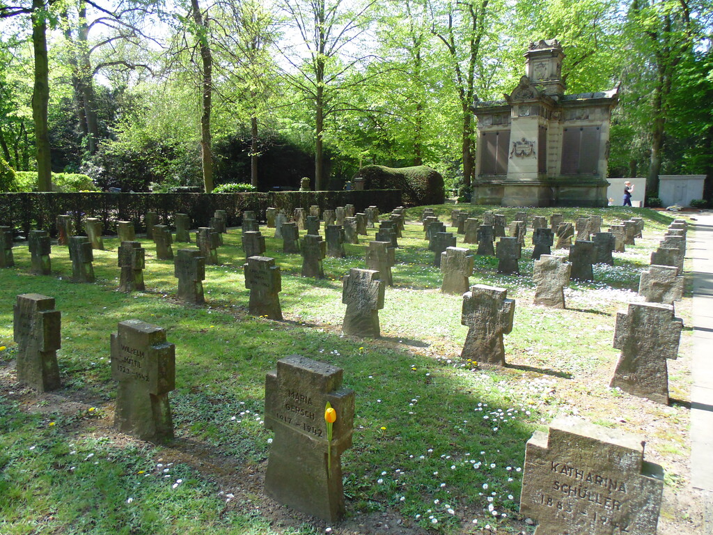 Gräberreihen des Zweiten Weltkriegs auf dem Kriegsgräberfeld V1 auf dem Melatenfriedhof in Köln-Lindenthal. Im Hintergrund ist das Kriegerdenkmal und Soldaten-Grabmal von 1870/71 zu sehen (2020)