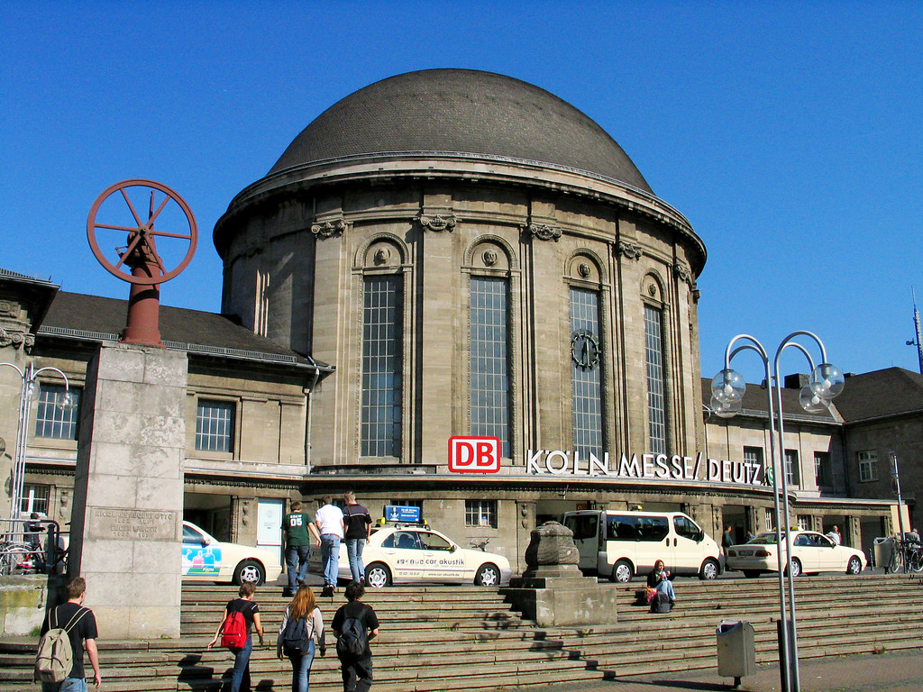 Das Empfangsgebäude des Bahnhofs Köln Messe/Deutz, links das Denkmal für Nikolaus August Otto auf dem Ottoplatz (2005).
