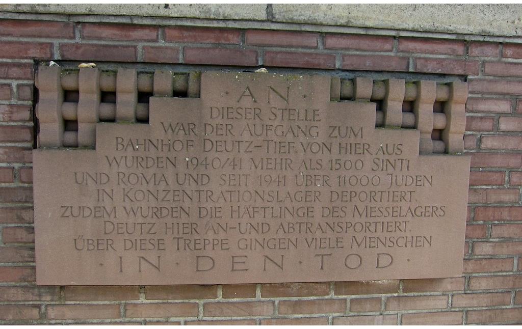 Die Gedenktafel zu den Deportationen während der NS-Zeit, die von den Bahnsteigen von "Deutz-Tief" ausgingen, am Eingang zum Bahnhof Köln Messe/Deutz am Auenweg (2015).