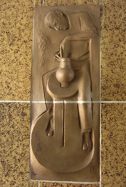 Wandkeramik im Durchgang des Geschäftshauses Hauptstraße 11 in Frechen. Die Keramik stellt einen Töpfer mit Drehscheibe dar (2013).