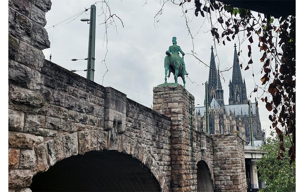 Rückwärtige Ansicht des Reiterstandbilds von Kaiser Friedrich III. an der Kölner Hohenzollernbrücke, dahinter der Dom (2021).