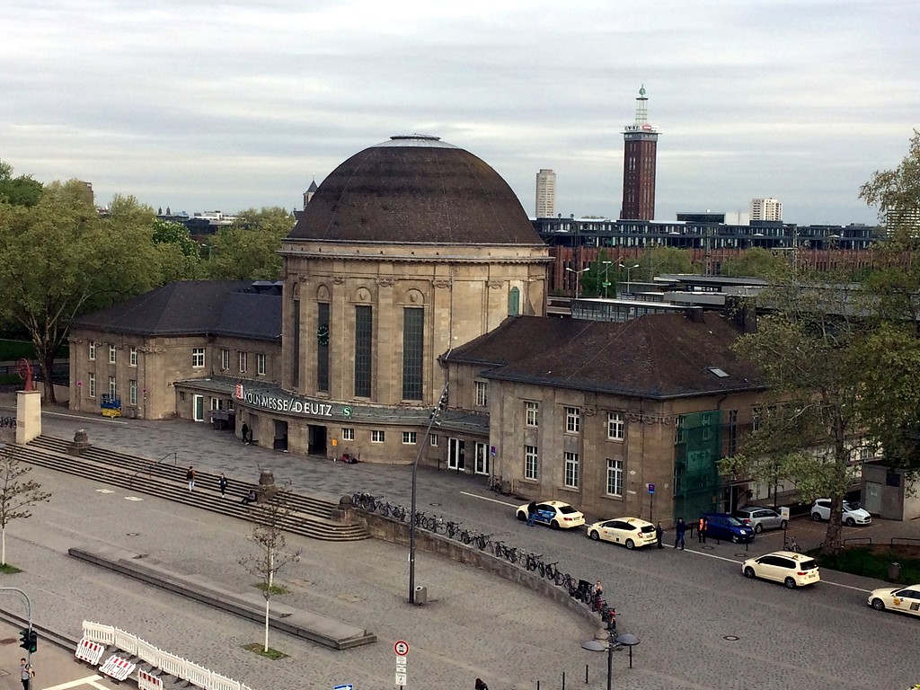 Empfangsgebäude des Bahnhofs Köln Messe/Deutz (2018) mit einem Teil des Bahnhofsvorplatzes, im Hintergrund der Messeturm.