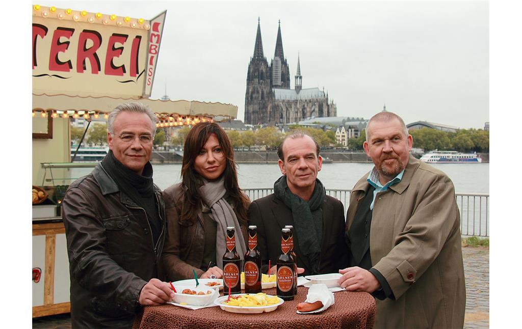 Die Ermittlerduos "Schenk & Ballauf" und "Keppler & Saalfeld" der "Tatort"-Kriminalfilme an der Kulisse des Schnellimbiss "Wurstbraterei" an der Deutzer Brücke. Im Hintergrund ist der Kölner Dom zu sehen (2012).