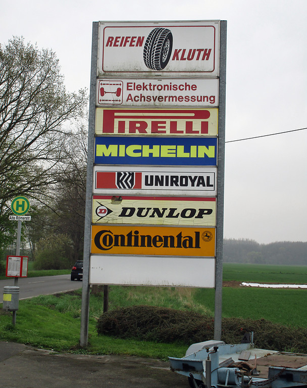 Werbetafel für verschiedene Autoreifen-Marken an der südlichen Ausfahrt von der historischen Tankstelle auf die alte Neusser Landstraße (2016).