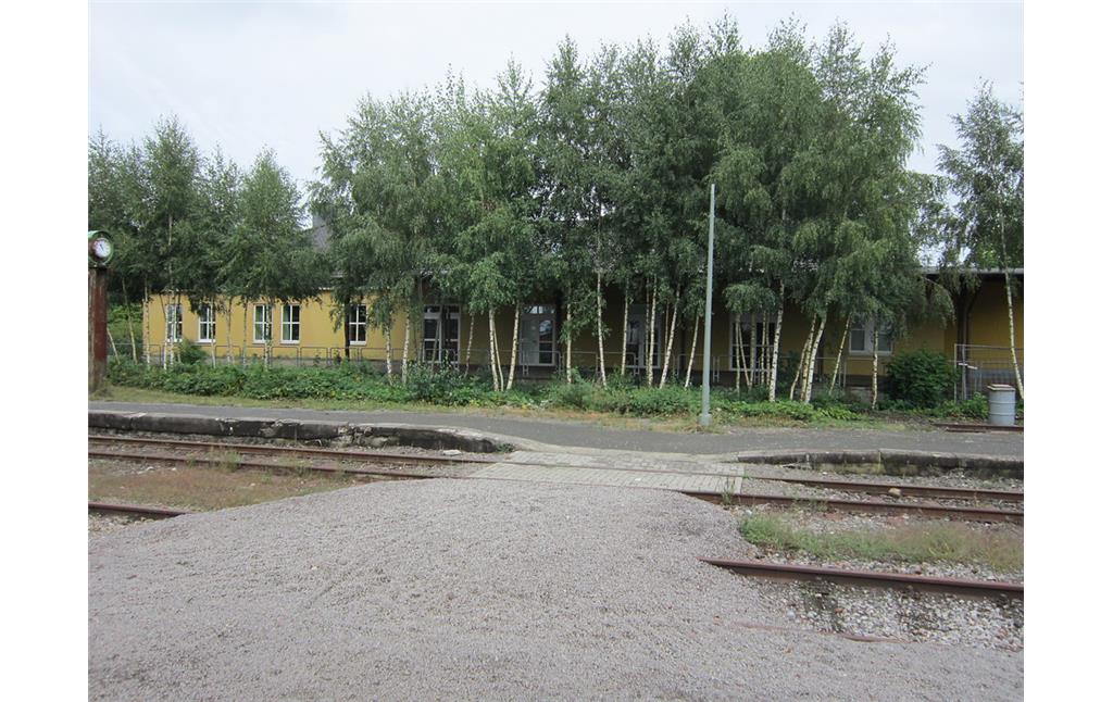Die Zollhalle des Bahnhofes Kranenburg, von der Bahnseite aus gesehen; im Vordergrund Reste der Gleisanlagen (2013)