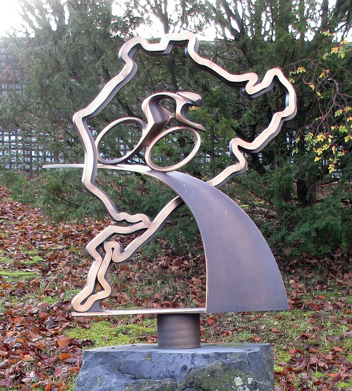Die bronzene Skulptur am Denkmal "Radsport am Nürburgring" stellt einen Radfahrer dar, der auf einer Bahn durch die bekannte Silhouette der Rennstrecke fährt (2020).