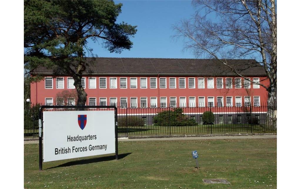 Ein Gebäude der militärischen Einrichtung "Joint Headquarters JHQ" in Rheindahlen, davor ein Hinweisschild auf das Hauptquartier der britischen Streitkräfte in Deutschland "Headquarter British Forces Germany" (2012).