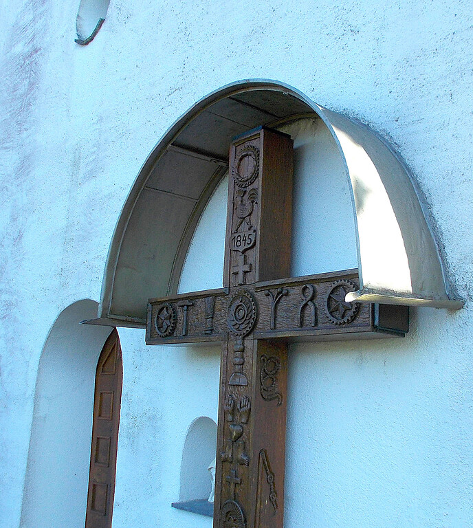 Aufwendig verziertes Holzkreuz von 1845 neben dem Eingang der Zilleskapelle
