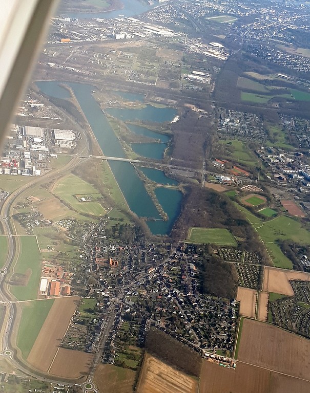 Blick vom Flugzeug aus auf den Kölner Stadtteil Fühlingen im Vordergrund und das Naherholungsgebiet Fühlinger See dahinter (2018). Links im Bild verläuft die Bundesstraße B 9, im Hintergrund sind Köln-Merkenich und -Seeberg und der Rhein zu sehen.