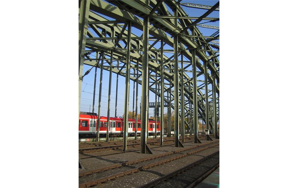 Teilansicht der Kölner Hohenzollernbrücke mit einer die Brücke befahrenden S-Bahn im Hintergrund (2012).