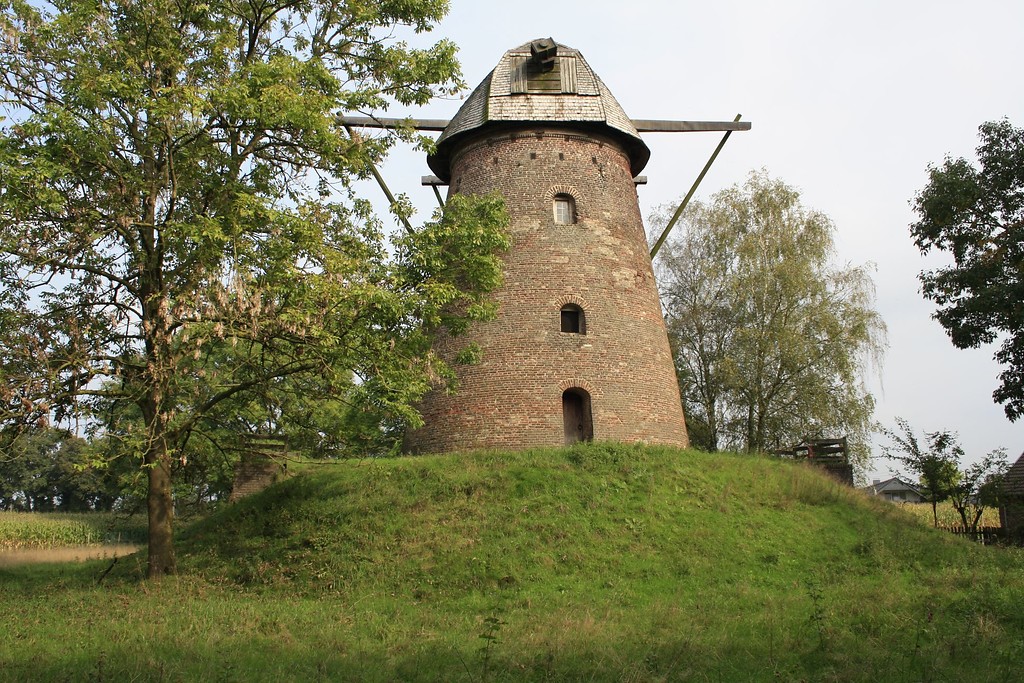 Der Turm der Nordbrocker Windmühle aus Backstein auf ihrem mit Gras bewachsenen angeschütteten Hügel von Westen aus (2014). Oben ist die Halterung für die Windmühlenflügel zu erkennen, die Flügel selbst jedoch fehlen.