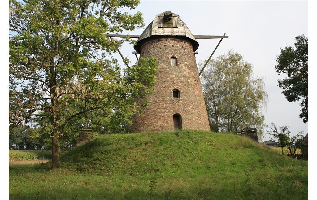 Der Turm der Nordbrocker Windmühle aus Backstein auf ihrem mit Gras bewachsenen angeschütteten Hügel von Westen aus (2014). Oben ist die Halterung für die Windmühlenflügel zu erkennen, die Flügel selbst jedoch fehlen.