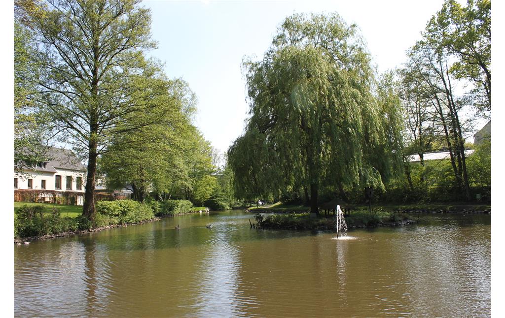Der Mühlenteich am Widemweg in Schermbeck-Gahlen. In der Mitte steht eine kleine baumbestandene Insel und ein Wasserspiel (2014).