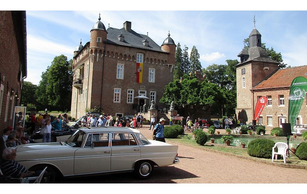 Das zentrale Haupthaus und die Vorburg von Schloss Loersfeld in Kerpen während der Oldtimer-Veranstaltung "Trips-Gedächtnisfahrt" (2022). Im Bildvordergrund ein Mercedes-Benz-PKW 300 SE der 1961-1967 produzierten Baureihe 112 ("Heckflosse").