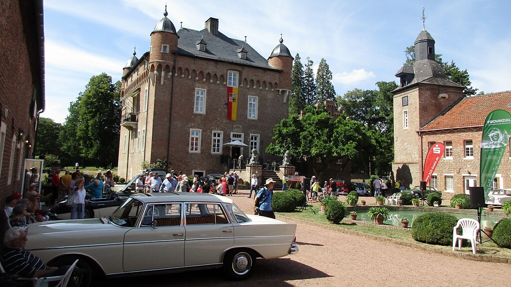 Das zentrale Haupthaus und die Vorburg von Schloss Loersfeld in Kerpen während der Oldtimer-Veranstaltung "Trips-Gedächtnisfahrt" (2022). Im Bildvordergrund ein Mercedes-Benz-PKW 300 SE der 1961-1967 produzierten Baureihe 112 ("Heckflosse").