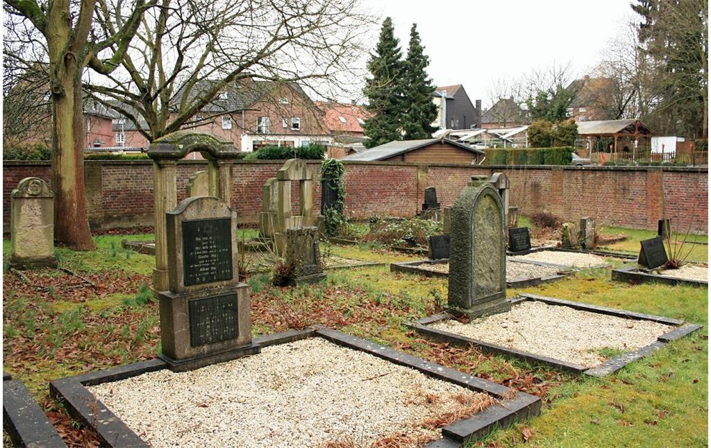 Grabsteine auf dem Gräberfeld im nördlichen Bereich des jüdischen Friedhofs Roßweide in Mönchengladbach-Wickrath (2015). In Blickrichtung der hinter der Friedhofsmauer gelegenen Straße "Am Kauert" befand sich möglicherweise der alte jüdischer Friedhof "Flieth".
