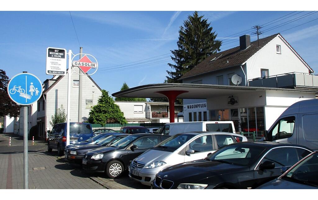 Die an der Hauptstraße in Troisdorf-Spich gelegene frühere Tankstelle (2022), heute als Autowerkstatt mit Gebrauchtwagenhandel und Wagenpflege genutzt.