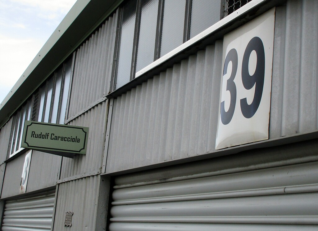 Namensstafel "Rudolf Caracciola" und Tafel Nr. 39 an der "Karratsch" gewidmeten Garagenbox in der südöstlichen Reihe der Boxen im historischen Fahrerlager am Nürburgring (2020).