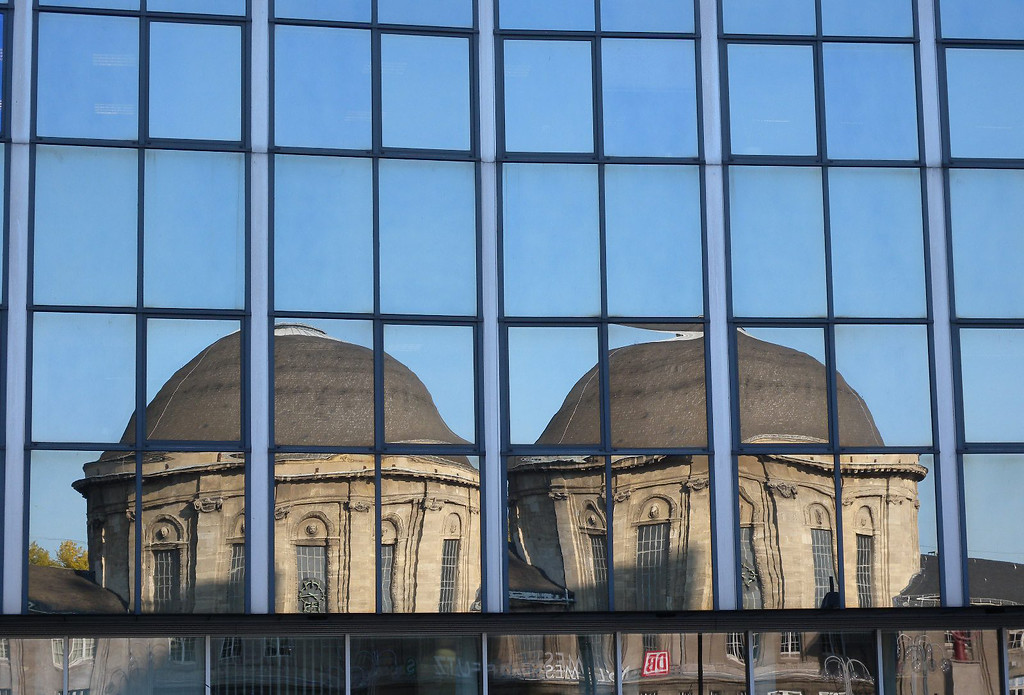 Ein doppeltes Spiegelbild des Kuppelbaus des Köln-Deutzer Bahnhofs Messe/Deutz in der Glasfassade des LVR-Hochhauses (2011).