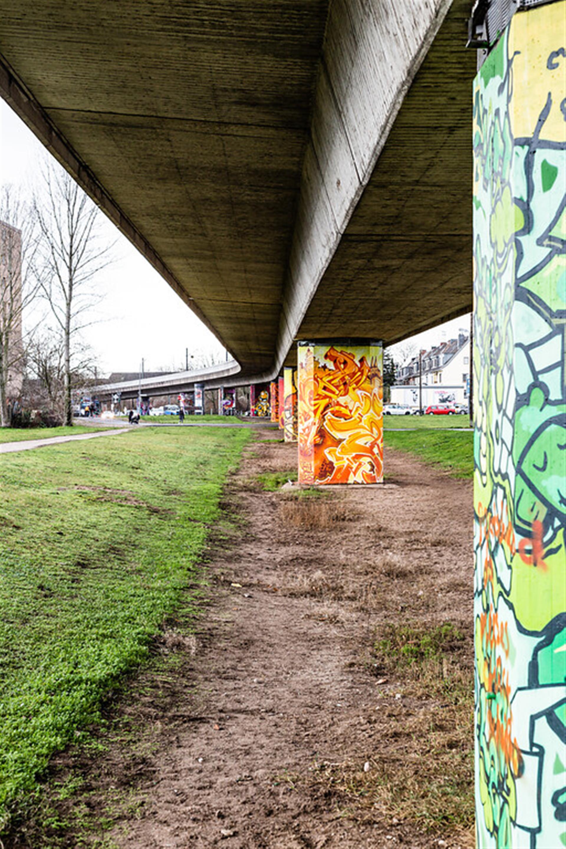 Jeder Brückenpfeiler der Hochbahn in Mauenheim ist unterschiedlich durch Streetart gestaltet worden (2021). &copy; Sebastian Löder / CC BY 4.0