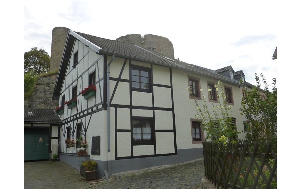 Haus in Kronenburg, dahinter die Burgruine (2014)
