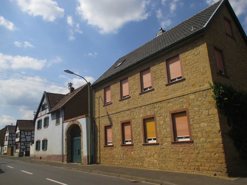 Straßenzeile in Embken mit traufständigem Bruchsteinhaus, weiß gestrichener Hofanlage mit Torbogen und zwei giebelständigen Fachwerkhäusern (2015)