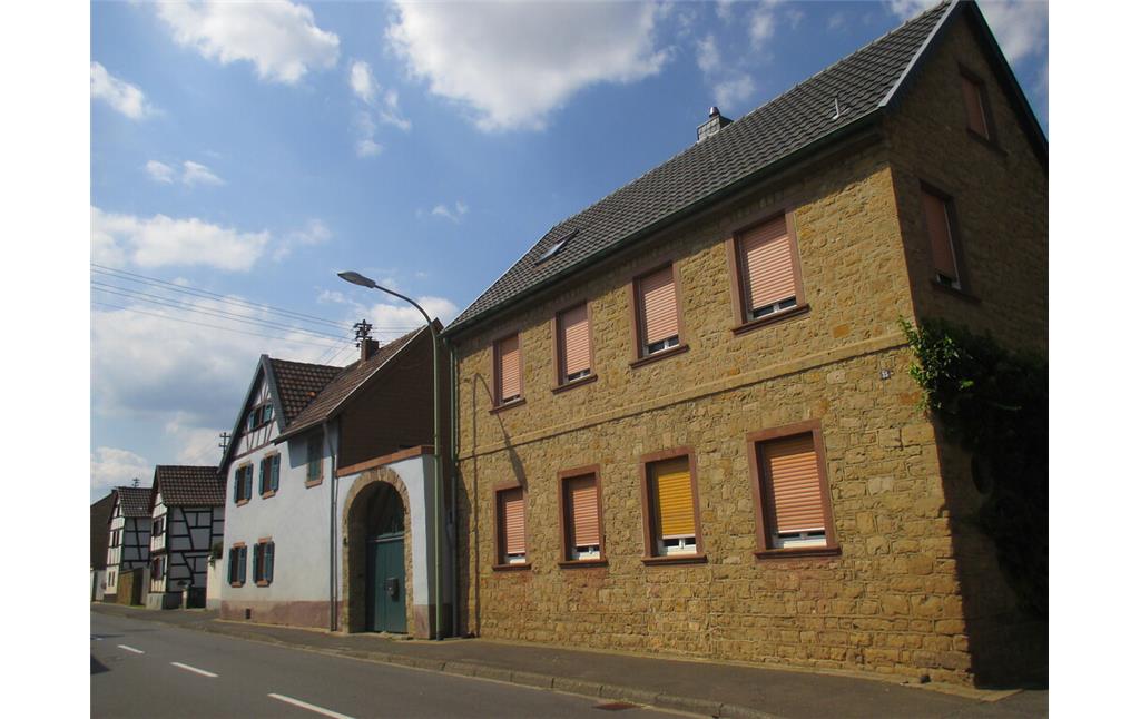Straßenzeile in Embken mit traufständigem Bruchsteinhaus, weiß gestrichener Hofanlage mit Torbogen und zwei giebelständigen Fachwerkhäusern (2015)