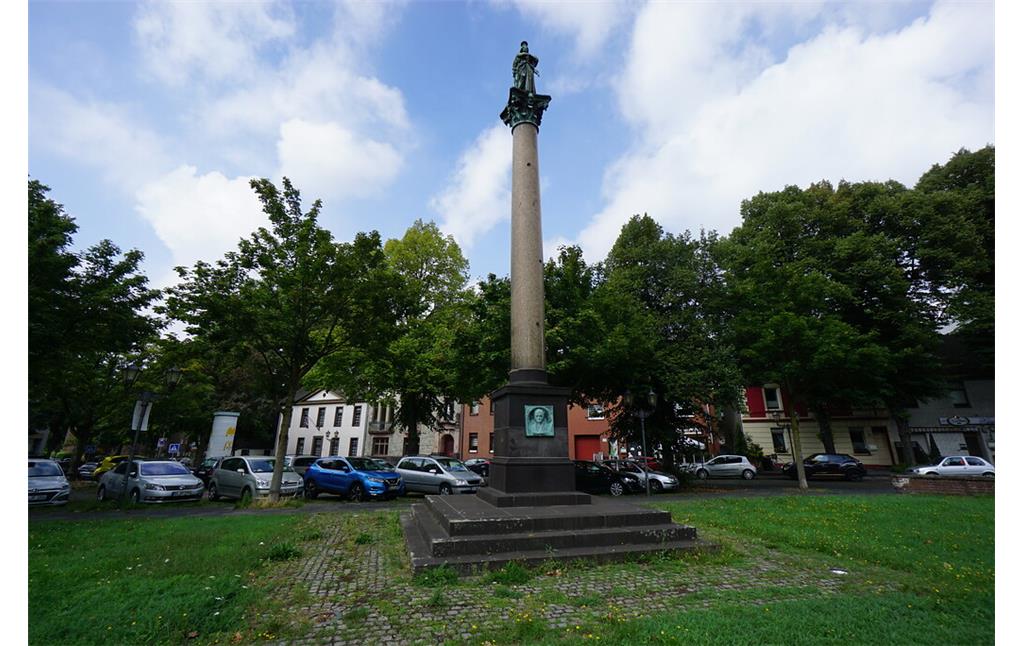 Die Vickesäule steht auf einem getreppten Sockel in einer Rasenfläche auf einem zentralen Platz in Ruhrort (2020).