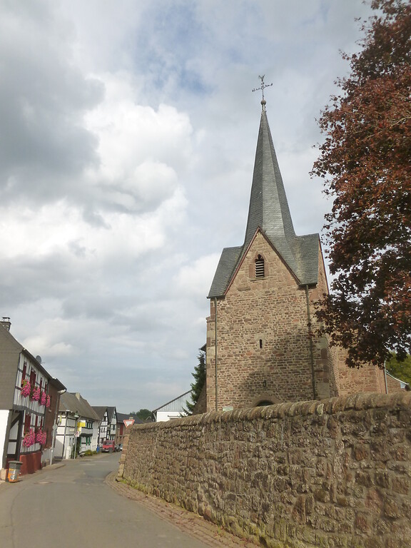 Westturm der Kapelle St. Hubertus und Zu den Heiligen Mauren in Hostel mit umgebender Bruchsteinmauer und gegenüberliegendem Fachwerkensemble (2014)