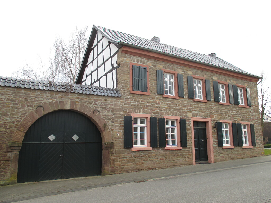 Traufständiges Haus in Boich mit Bruchsteinfassade, Torbogen in der Hofmauer, Fachwerkgiebel und mit grünen Läden an in Sandstein gefassten Fenstern (2015)