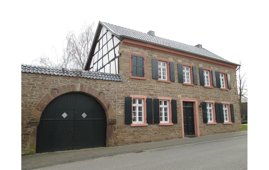 Traufständiges Haus in Boich mit Bruchsteinfassade, Torbogen in der Hofmauer, Fachwerkgiebel und mit grünen Läden an in Sandstein gefassten Fenstern (2015)