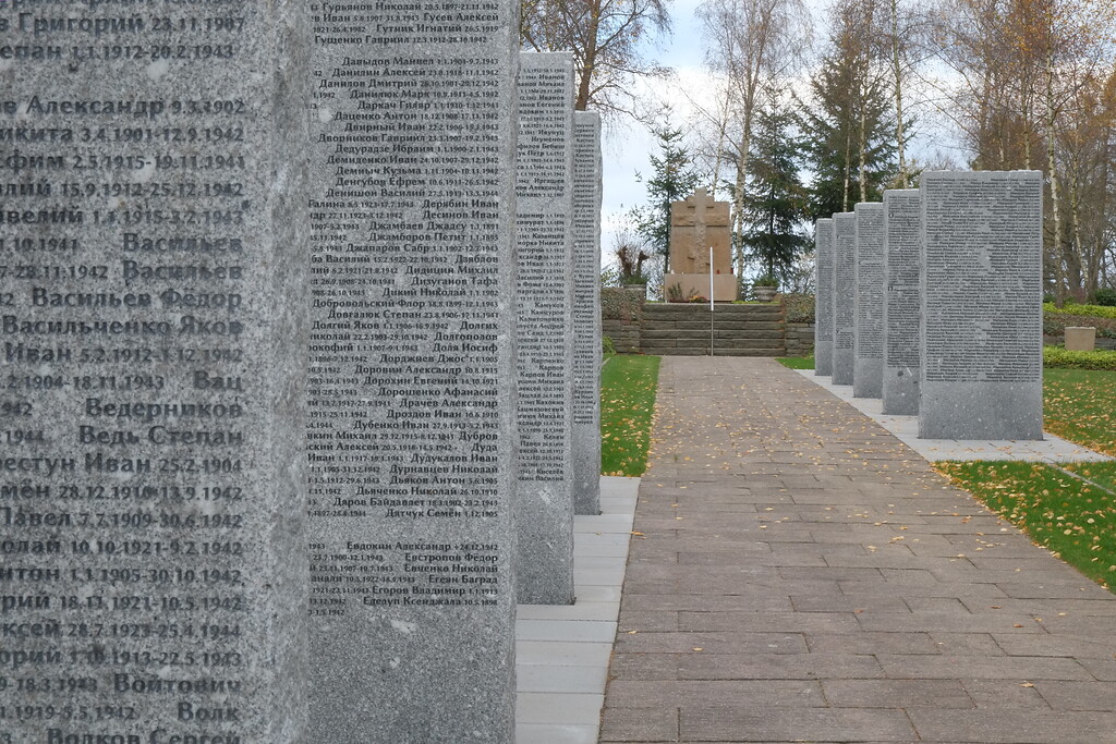 Bild 14: Die zehn Stelen auf der Gräberstätte Rurberg rechts und links des Mittelweges mit Blick auf das russisch-orthodoxe Hochkreuz (2015). Verzeichnet sind darauf Namen und Daten von 2.485 toten sowjetischen Zwangsarbeitern und Zwangsarbeiterinnen.