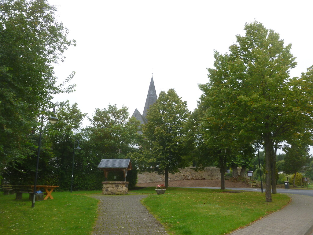 von Linden gerahmte Grünfläche mit Sitzgruppe und altem Dorfbrunnen in Dottel (2014)