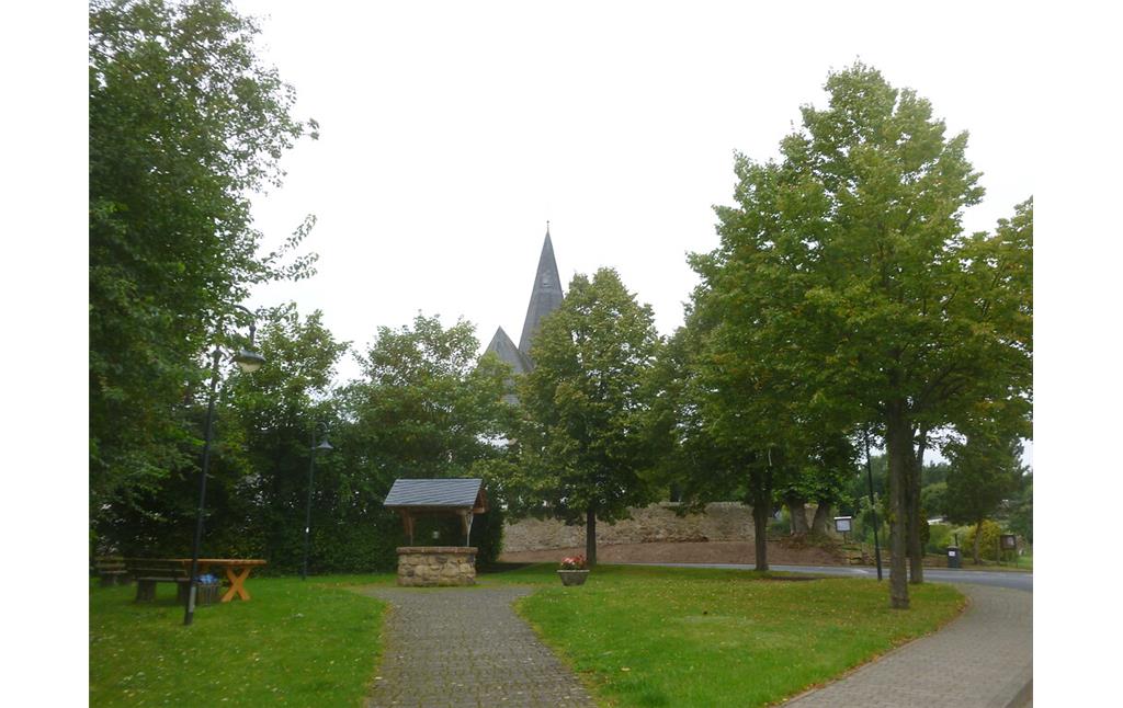 von Linden gerahmte Grünfläche mit Sitzgruppe und altem Dorfbrunnen in Dottel (2014)