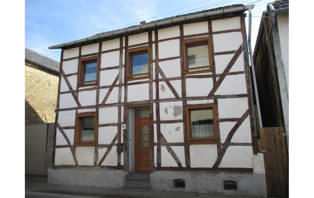 Bei diesem traufständigen Fachwerkgebäude auf Bruchsteinsockel in Muldenau ist die Fassade regelmäßig durch mit Holz eingefasste Fenster gegliedert. (2015)