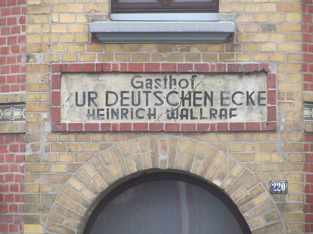 Inschrift über der ehemaligen Eingangstür des Gasthofes. Sie lautet: "Gasthof ZUR DEUTSCHEN ECKE / HEINRICH WALLRAF (2014)