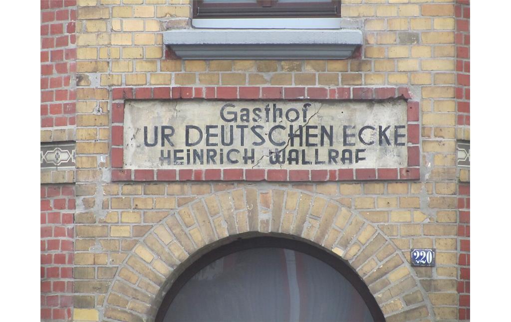 Inschrift über der ehemaligen Eingangstür des Gasthofes. Sie lautet: "Gasthof ZUR DEUTSCHEN ECKE / HEINRICH WALLRAF (2014)