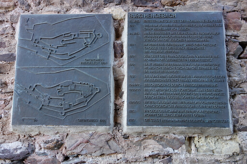 In eine Burgmauer in Tornähe ist eine Informationstafel eingelassen, auf der die wichtigsten Eckdaten der Burg über die Jahrhunderte hinweg sowie ihr Grundriss verzeichnet sind (2020).