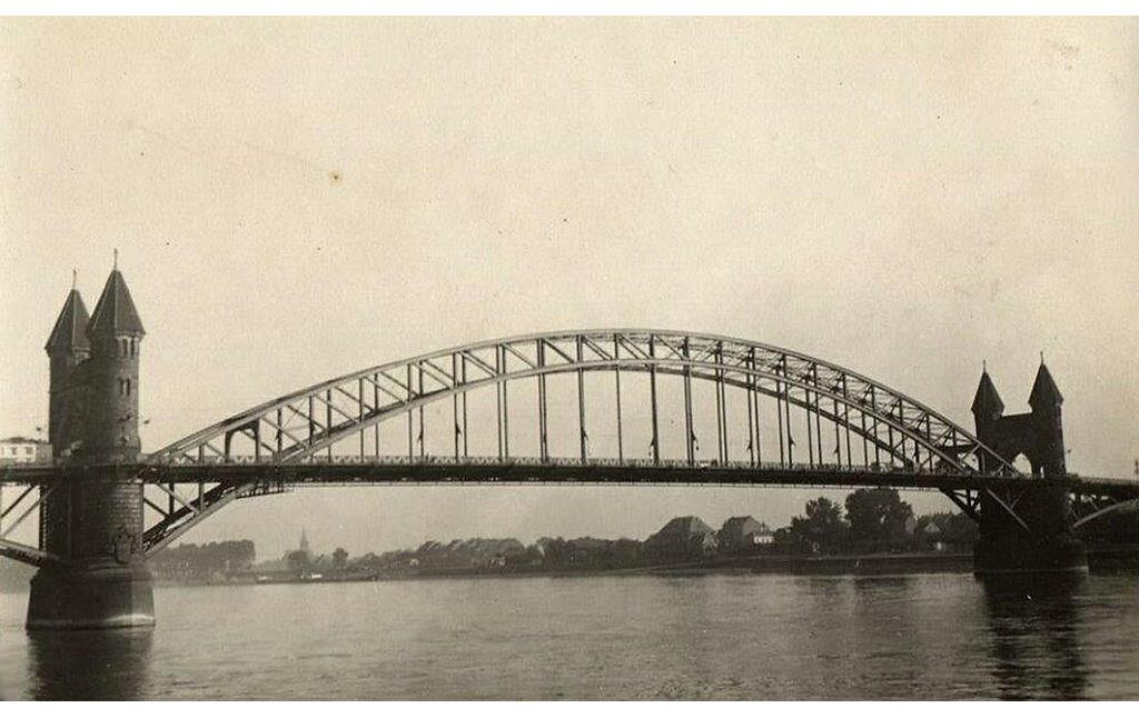 Auf das Jahr 1930 datierte Aufnahme der Alten Bonner Rheinbrücke, das 1945 zerstörte Vorgängerbauwerk der heutigen Kennedybrücke. Das Bild wurde auf der Bonner Rheinwerft mit Blick nach Norden aufgenommen.