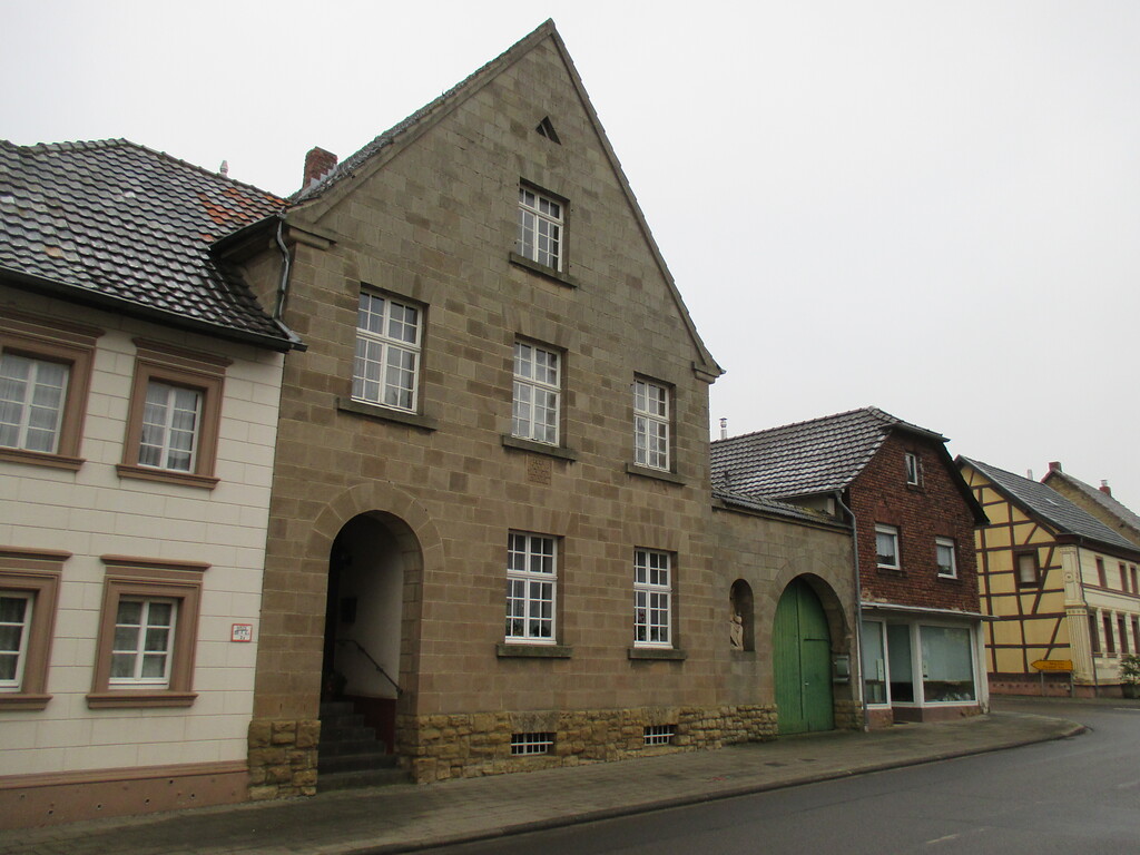 Haus in Bürvenich mit hoher Giebelfront sowie regelmäßig angeordneten Fenstern und Rundbogen zur Eingangstür auf (2014)