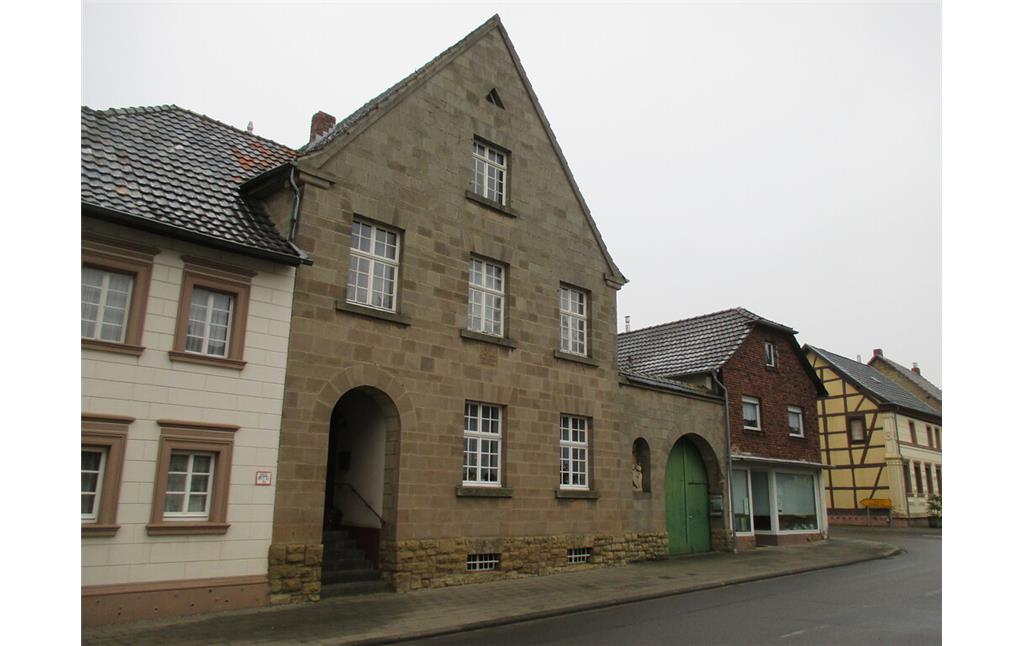 Haus in Bürvenich mit hoher Giebelfront sowie regelmäßig angeordneten Fenstern und Rundbogen zur Eingangstür auf (2014)