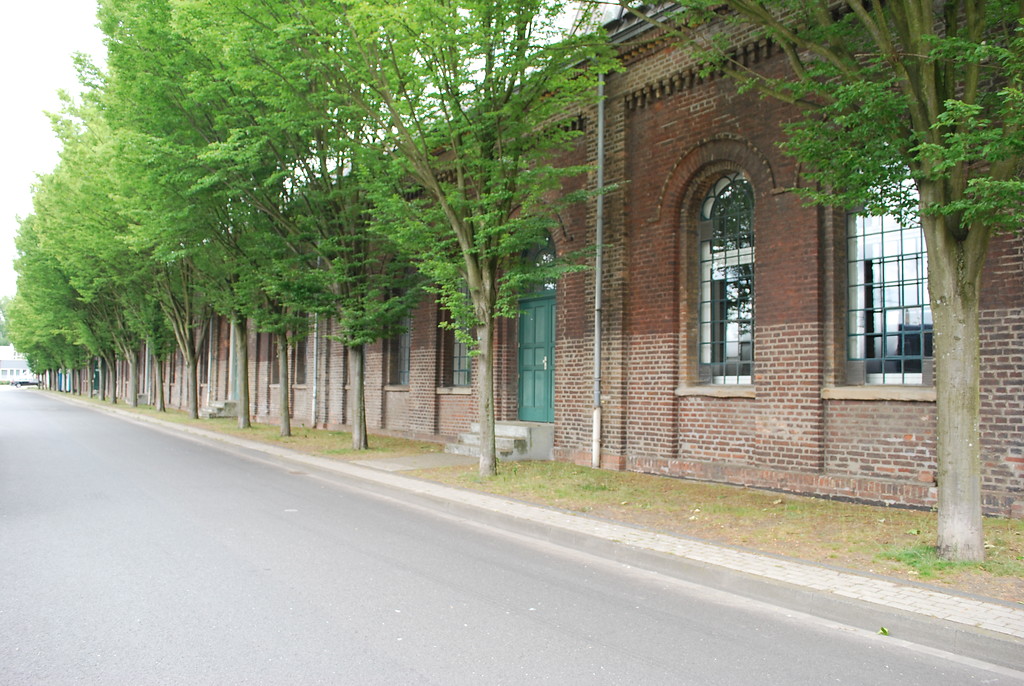 Die Werkstatt der Zeche Rheinpreußen I/II war in einer langgestreckten Backsteindoppelhalle untergebracht. Sie hat Rundbogenfenster, gliedernde Wandelemente und ein Traufgesims mit Klötzchenfries. Heute nutzen Gewerbebetriebe das Gebäude (2015).