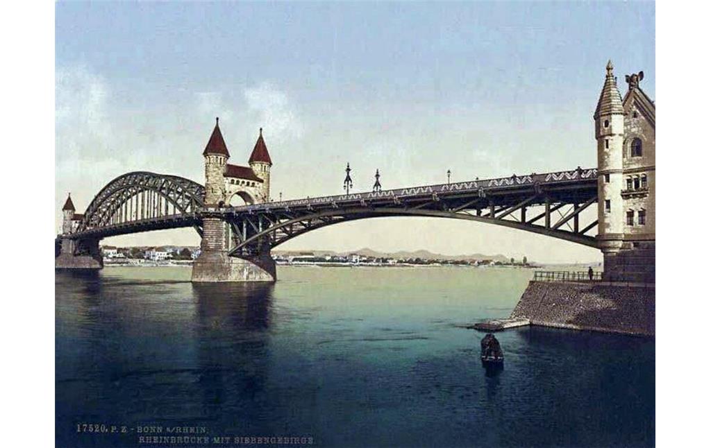 Die undatierte Farbpostkarte "Bonn a/Rhein, Rheinbrücke mit Siebengebirge" zeigt die Alte Rheinbrücke vom Bonner Flussufer aus.