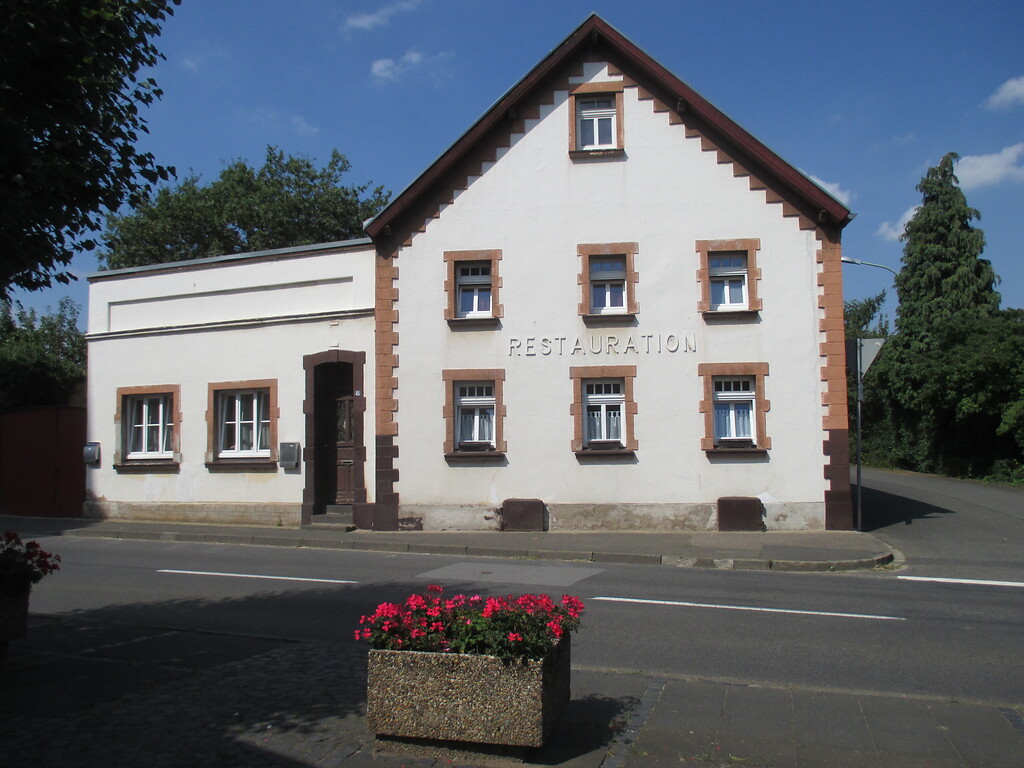 giebelständige ehemalige Restauration mit in rotem Sandstein eingefassten, regelmäßig angeordneten Fenstern und Anbau mit Pultdach in Embken (2015)