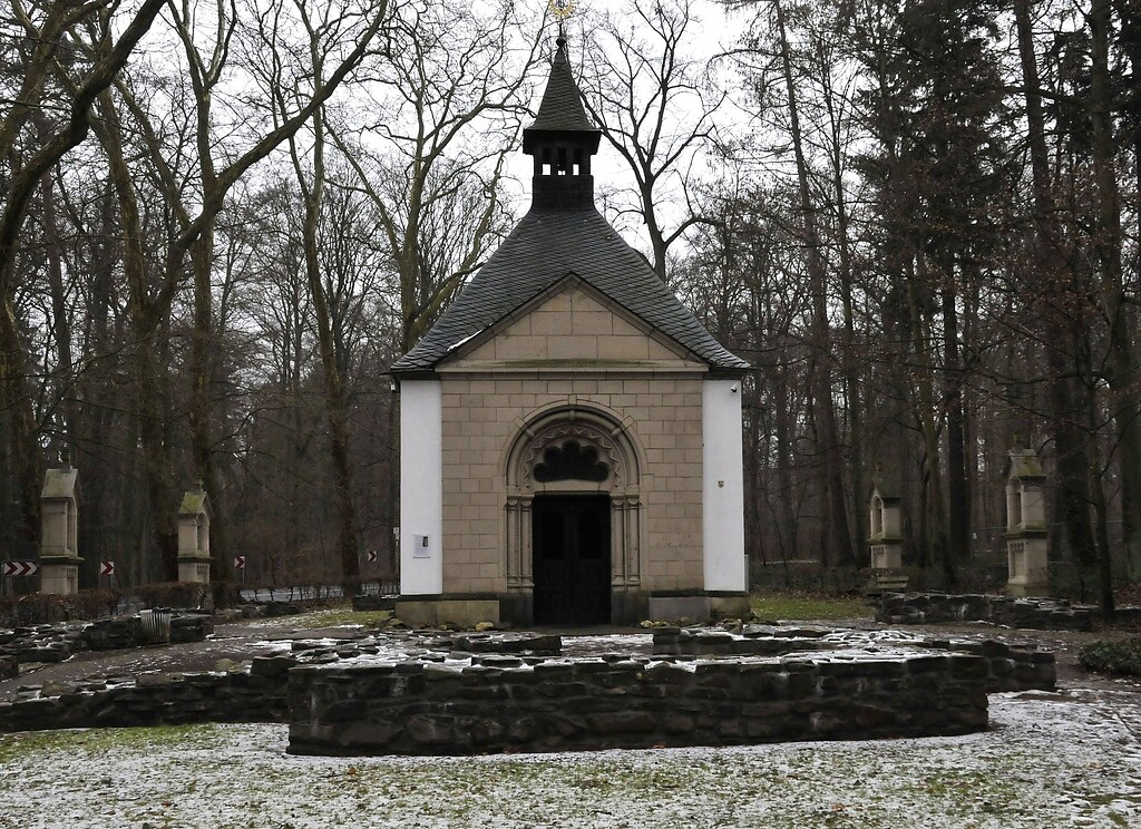 Nordseite der Waldkapelle bei Rheinbach mit Blick auf den Eingang. Um die Kapelle sieht man Stationen des Kreuzwegs Jesu.