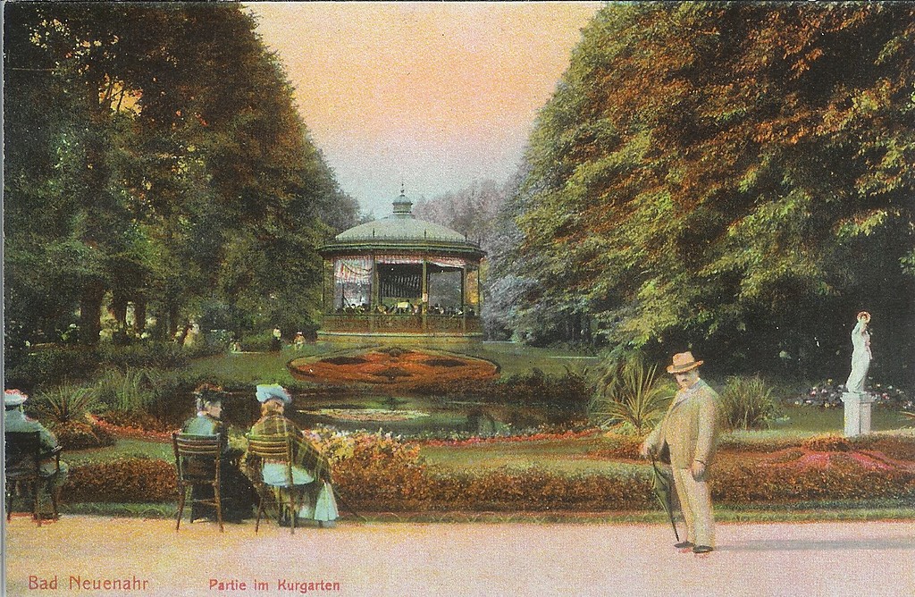 Blick auf den zentralen Kurparkbereich in Bad Neuenahr mit beidseitiger Ulmenallee, Wasserbecken, Teppichbeeten und Musikpavillon. Historische Postkarte um 1905.